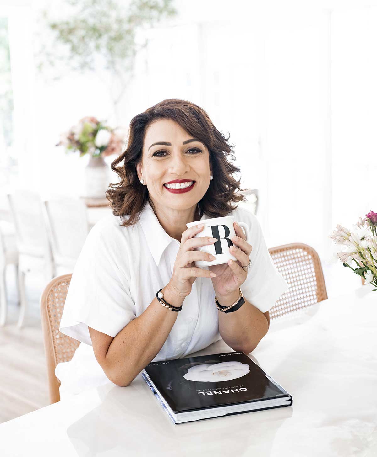 The Perth Fashion Stylist Rosalinda Panton sitting at kitchen table holding a cup of tea